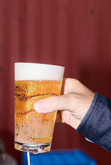 Hand hält einGlas mit frisch gezapftem, goldgelbem Bier und dichter Schaumkrone.